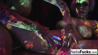 Black-light babes Nadia and Ophelia suck off a colorful cock