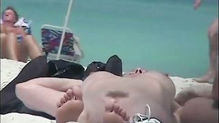 A nude tanned skinny lady with perfect breasts on a beach texting